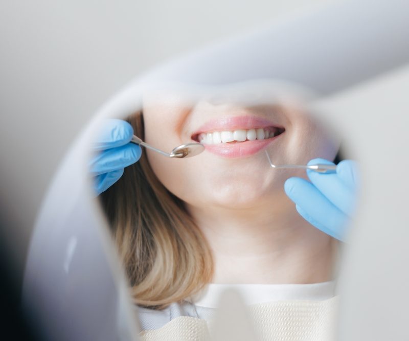 Caries treatment concept, Caucasian young female at dental checkup with dentist in blue gloves in stomatology clinic.