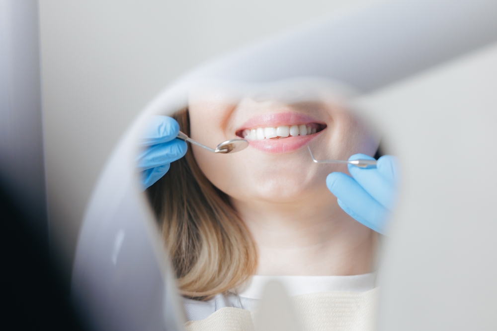 Caries treatment concept, Caucasian young female at dental checkup with dentist in blue gloves in stomatology clinic.