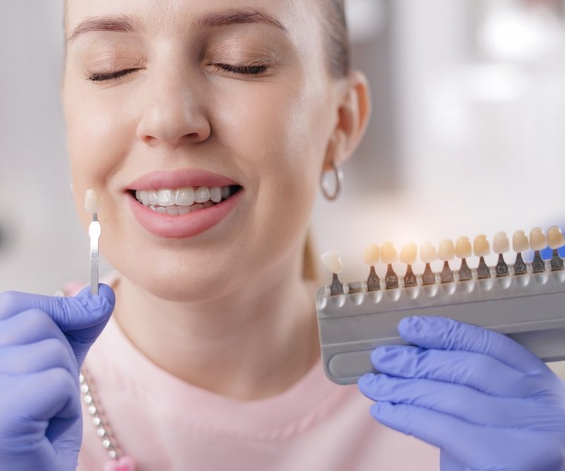 Caucasian female choosing dental veneers at dentist office.