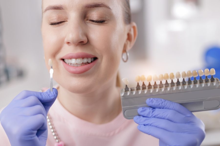 Caucasian female choosing dental veneers at dentist office.