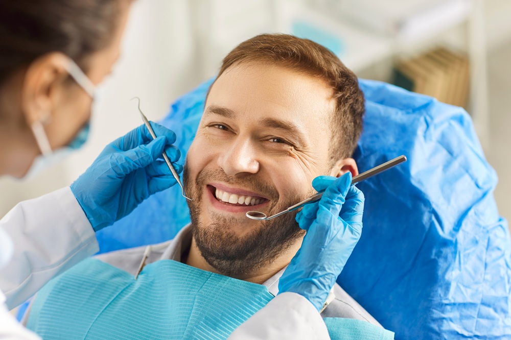 Happy Patient Showing Results of Smile Makeover - Benefits of Smile Makeover Smiling male patient in dental chair during treatment, highlighting improved confidence and aesthetic results from a smile makeover - Benefits of Smile Makeover