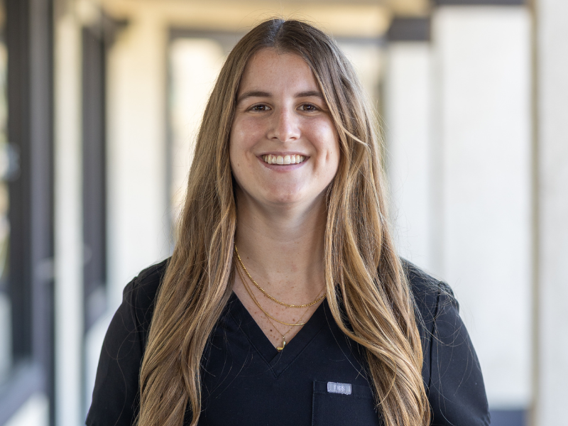 Portrait of Dr Megan in black scrubs smiling with arms crossed in a modern office setting, representing a trusted dentist in Hillcrest San Diego - Dentist Hillcrest San Diego