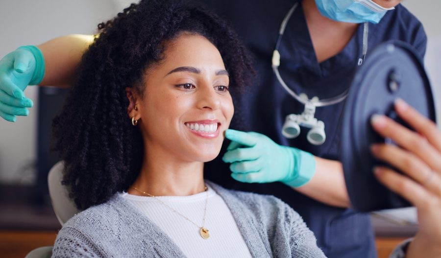 Woman, smile and mirror for checkup with dentist, oral hygiene and mouth cleaning service. Female person, assessment and orthodontic inspection for dental care, patient and help for consultation
