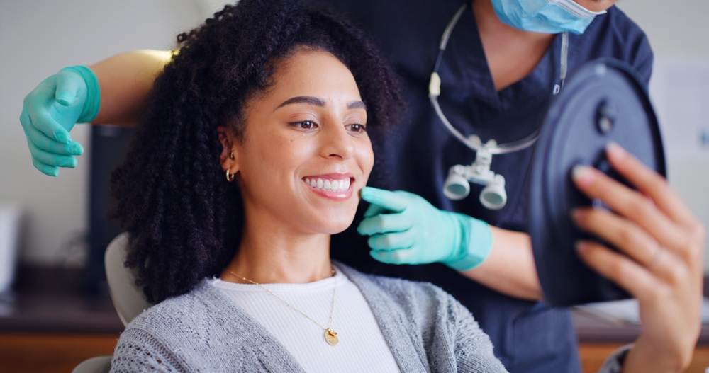 Woman, smile and mirror for checkup with dentist, oral hygiene and mouth cleaning service. Female person, assessment and orthodontic inspection for dental care, patient and help for consultation
