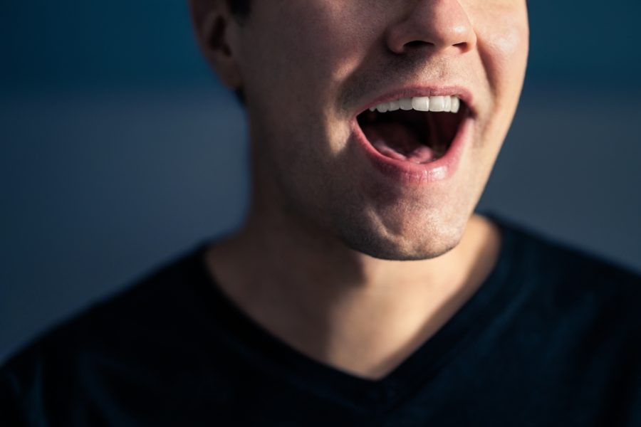 Close-up of a person with mouth open showing tongue and teeth, representing oral hygiene and the benefits of using a tongue scraper - Is a Tongue Scraper Good